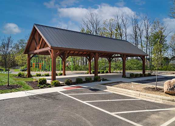 A covered wooden structure sits in the middle of a parking lot.