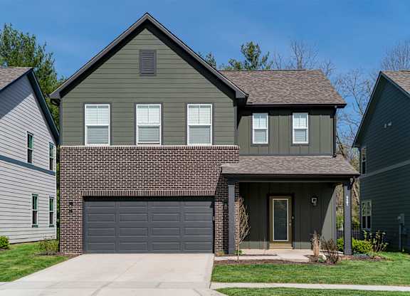 A house with a grey garage door is in front of two other houses.
