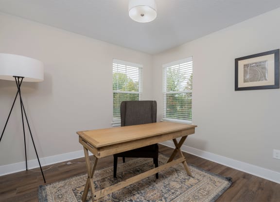 a room with a desk and a chair and two windows