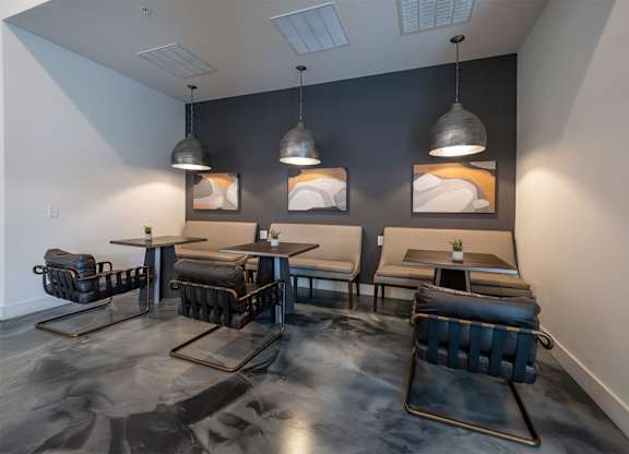 A room with black chairs and tables with a grey floor.