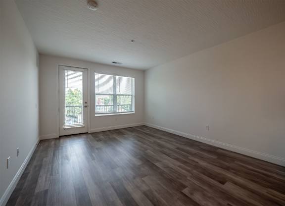 A room with a sliding glass door and wood flooring.