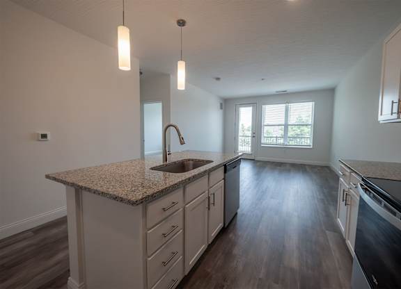 A kitchen with a granite countertop and wooden floors.