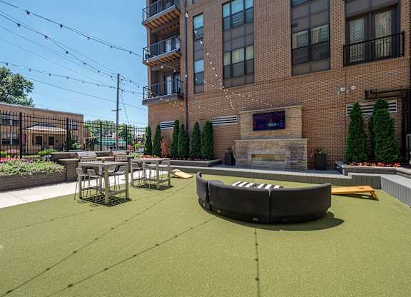 A patio area with a fire pit and seating area in front of a brick building.