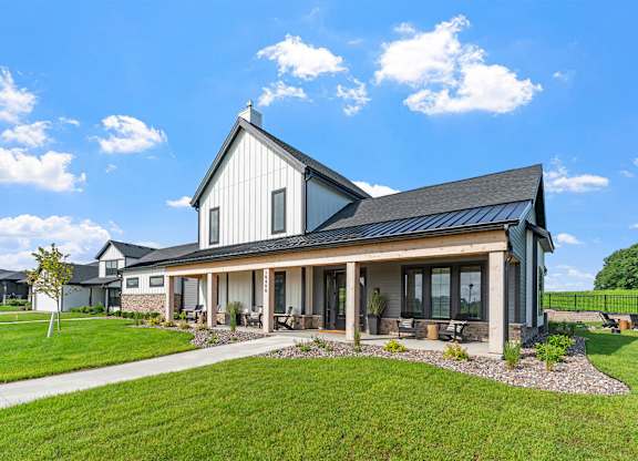 A modern house with a black roof and a large front porch.