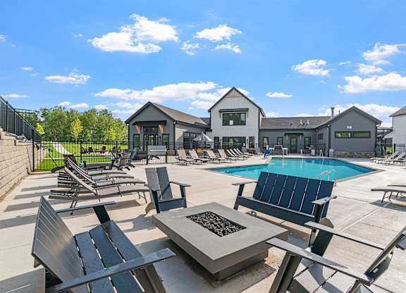 A sunny day at the pool with a fire pit in the middle.