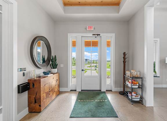 A white hallway with a green rug and a mirror on the wall.