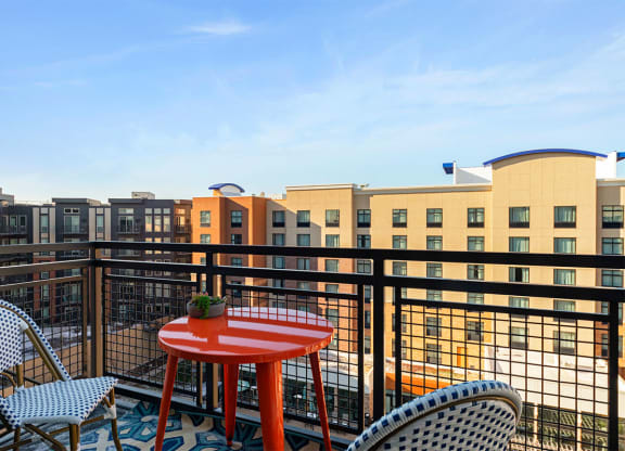 a patio with a red table and chairs on a balcony