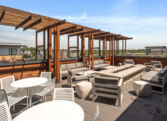 a rooftop patio with tables and chairs and a fire pit