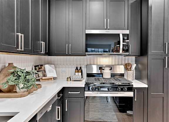 A modern kitchen with dark grey cabinets and a white countertop.