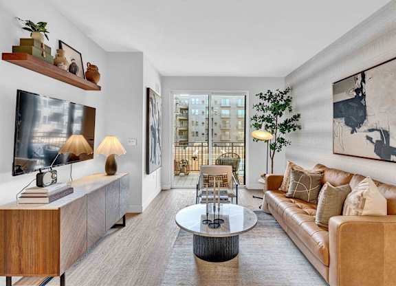A living room with a brown couch, a coffee table, and a painting on the wall.