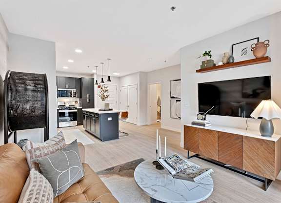A modern living room with a brown leather couch and a wooden entertainment center.