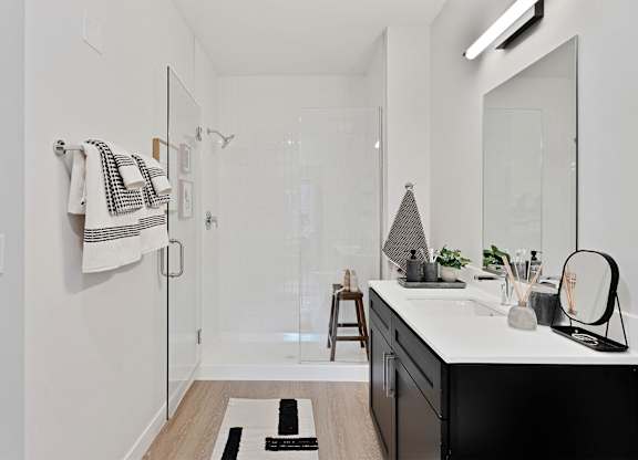 A bathroom with a white counter and a black and white striped towel hanging on the wall.