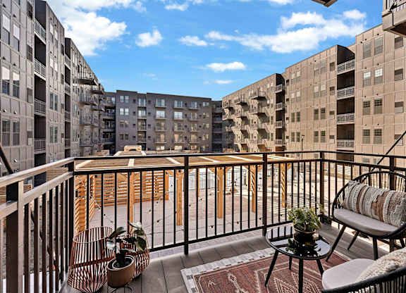 A balcony with a table and chairs overlooks a courtyard.