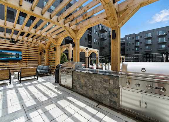 A wooden pergola over a barbecue grill on a patio.