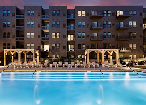 A large swimming pool in front of apartment buildings.