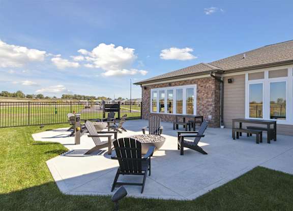A sunny day at a patio with a table and chairs.