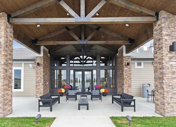 A covered patio with black furniture and pillows.