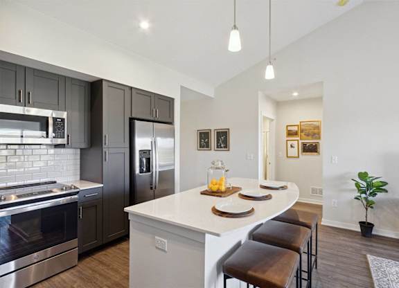 A modern kitchen with a white island and stainless steel appliances.