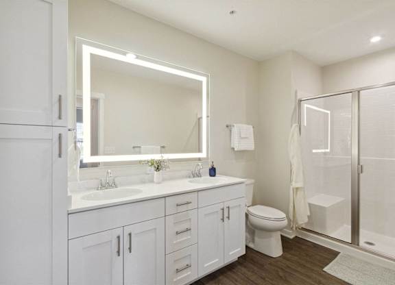 A white bathroom with a sink, toilet, and mirror.