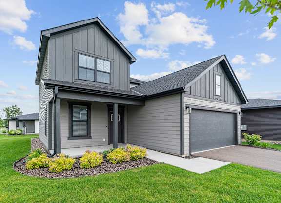 A modern house with a grey exterior and a large front yard.