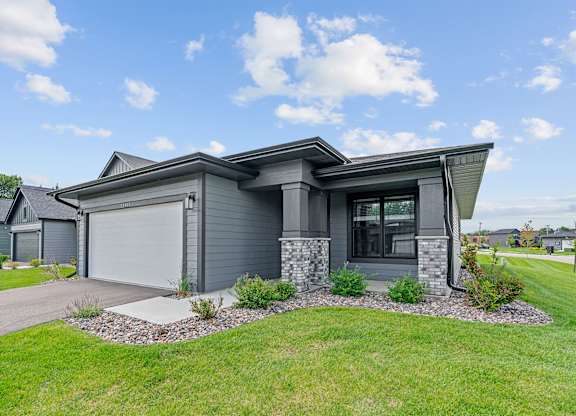 A modern house with a grey exterior and a stone pillar.