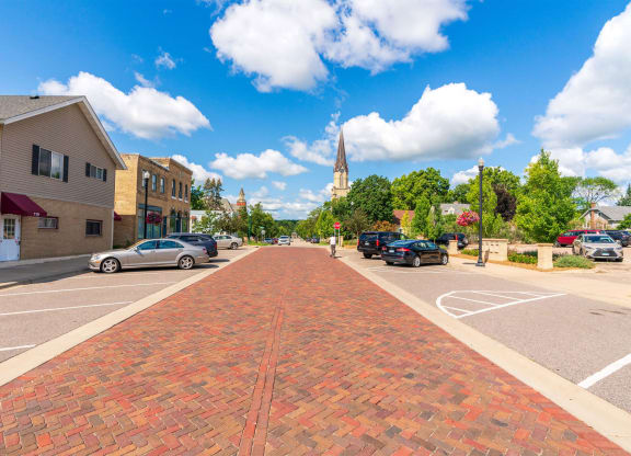 a city street with a brick sidewalk and a church in the distance