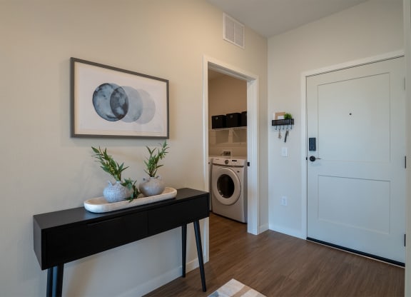 a living room with a washer and dryer and a door to a bathroom