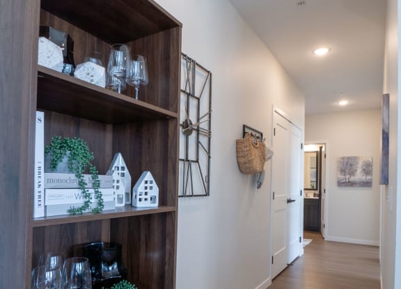 a hallway with a cabinet and shelves and a hallway leading to a door