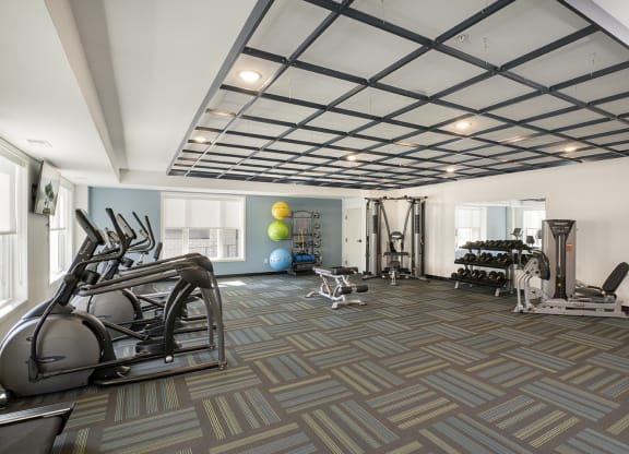a gym with treadmills and other exercise equipment in a large room with windows