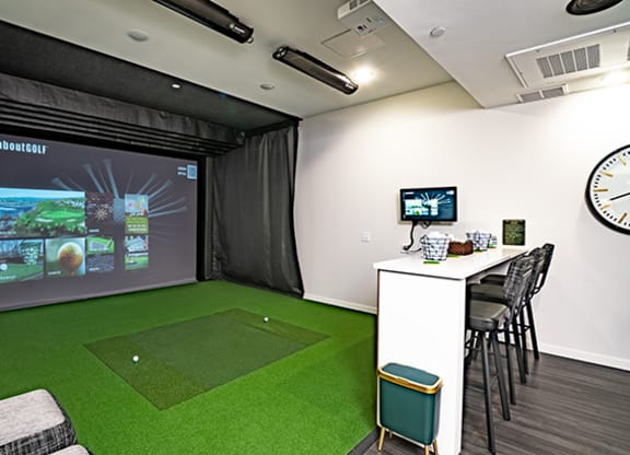 a room with a golf simulator and a video game on the wall