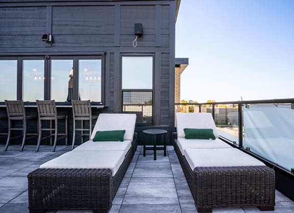 a rooftop terrace with couches and a table with chairs and a glass wall