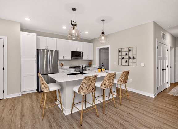 A kitchen with a white island and chairs.