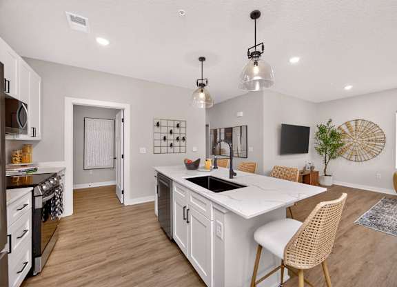 A kitchen with a white island and a dining table with chairs.