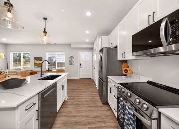 A modern kitchen with white cabinets and black appliances.