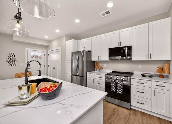 A modern kitchen with white cabinets and a marble countertop.