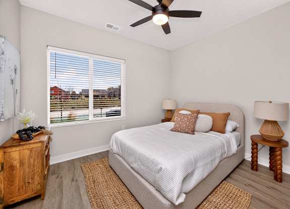 A bedroom with a bed, a ceiling fan, and a window with blinds.