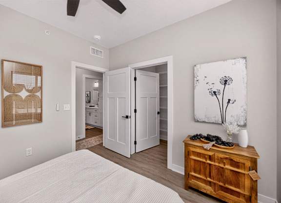 A bedroom with a bed, dresser, and artwork.