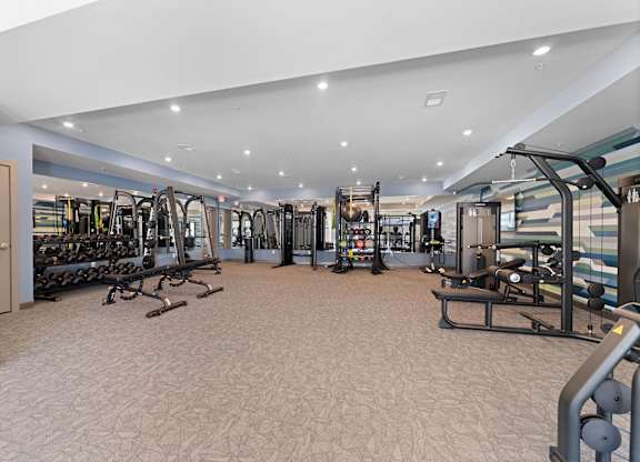 A gym with a variety of equipment including treadmills, weights, and exercise machines.