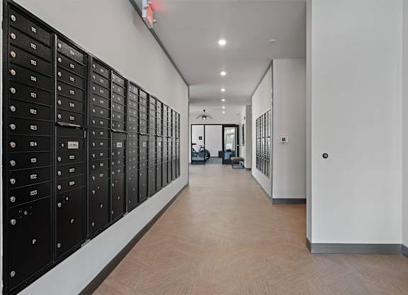 A long hallway with black mailboxes on the wall.