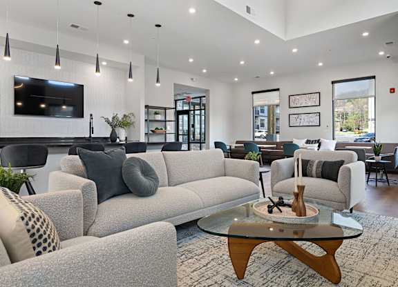 A modern living room with a grey sofa and a glass coffee table.