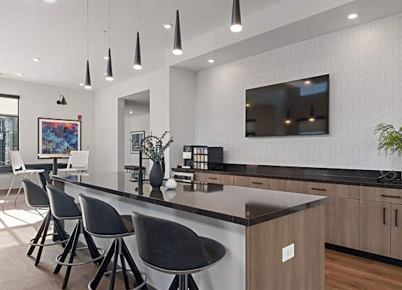 A modern kitchen with a bar area and chairs.