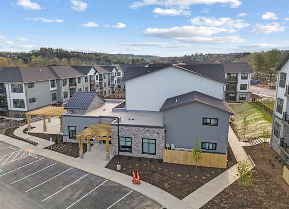 A parking lot is in front of a building with a grey roof.