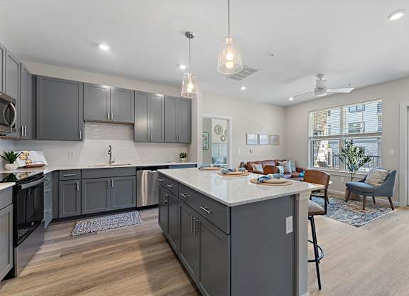 A modern kitchen with a large island and grey cabinets.
