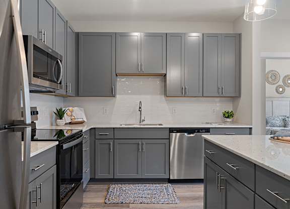 A kitchen with grey cabinets and a white countertop.