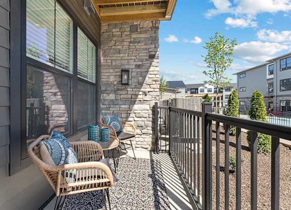A patio with a wicker chair and a stone pillar.