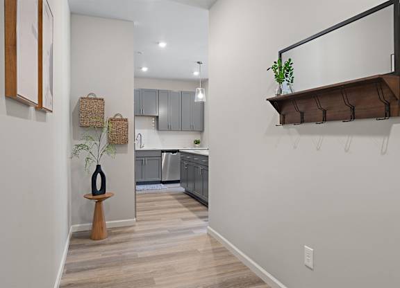 A kitchen with a white wall and a wooden floor.