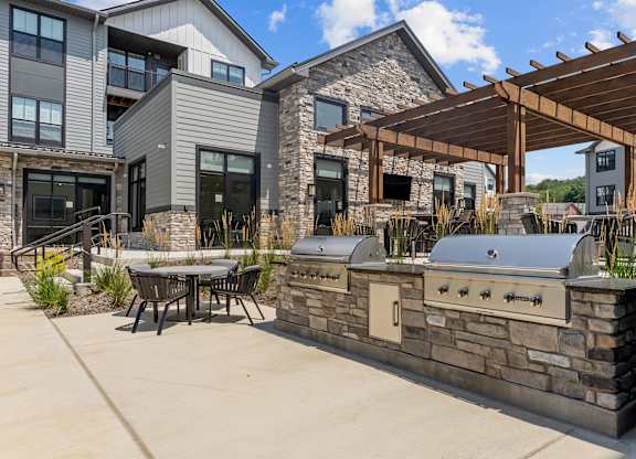 A modern house with a stone wall and a wooden pergola.