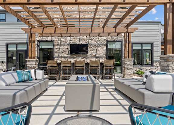 A patio with a stone wall and a wooden pergola.