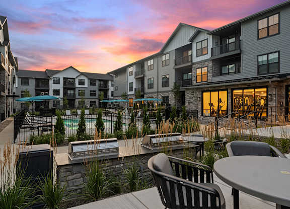 A sunset view of a resort with a pool and chairs.
