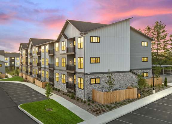 A modern apartment complex with a parking lot in front.